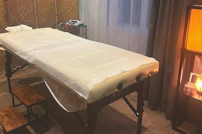 Private treatment room with a professional treatment table and warm lamp light